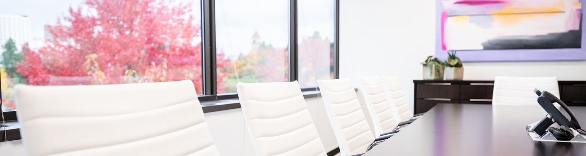 image of chairs at a board room table with colorful tree in the window